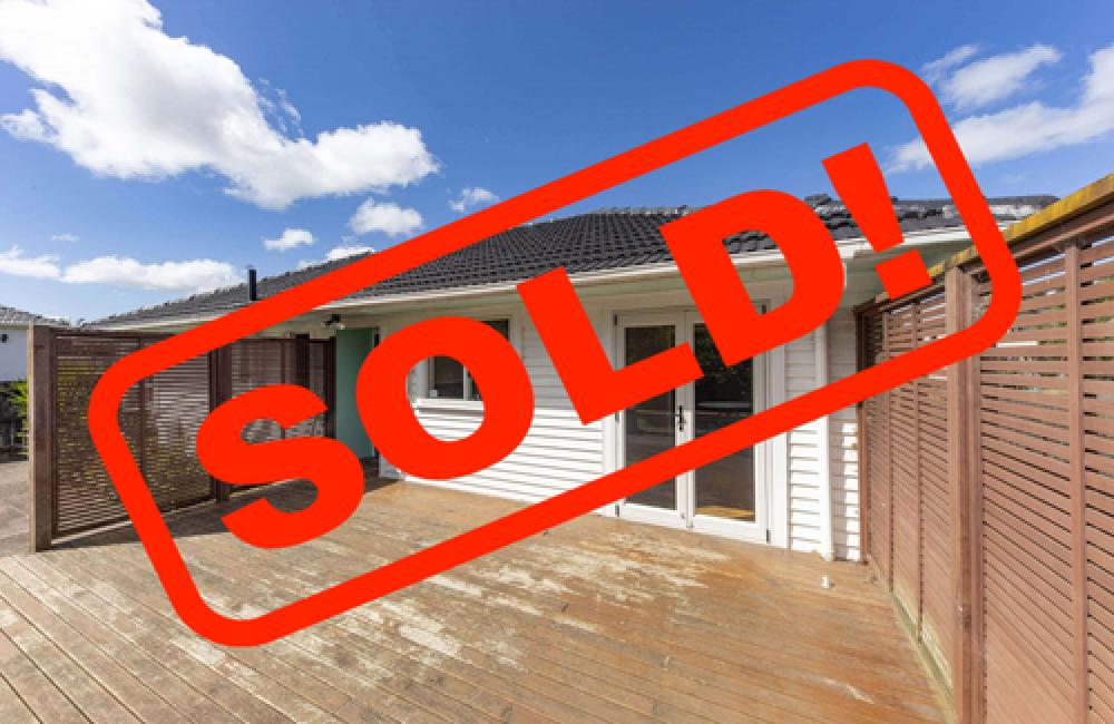 Wooden deck and house exterior with large red “SOLD!” stamp across the image