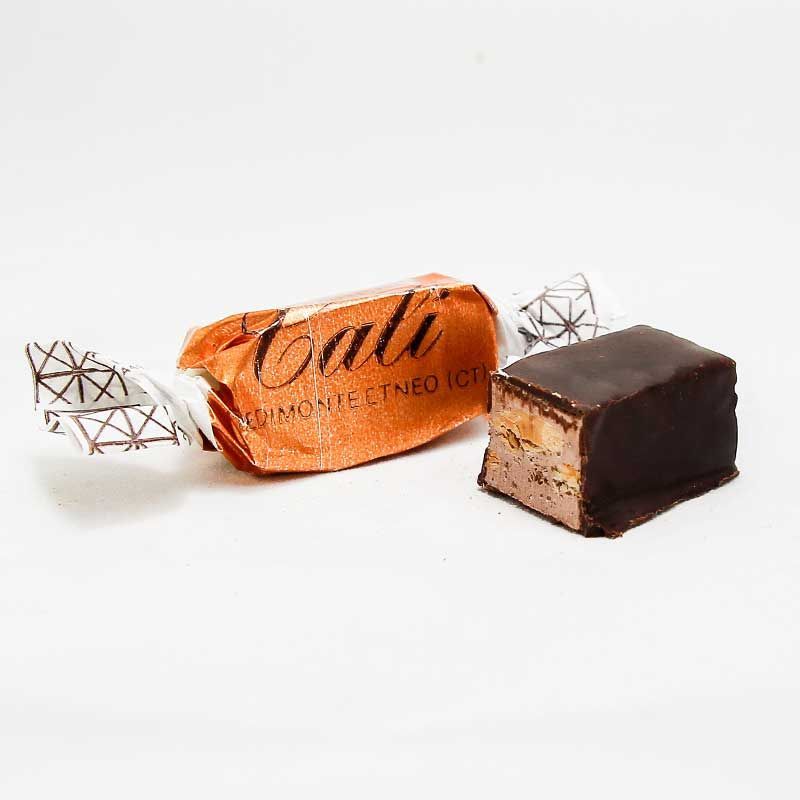 Primo piano di un pezzo di cioccolato su una superficie bianca.