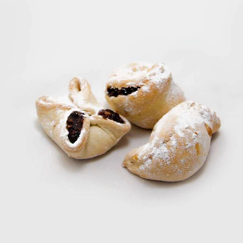 Un primo piano di tre pasticcini con zucchero a velo su una superficie bianca.