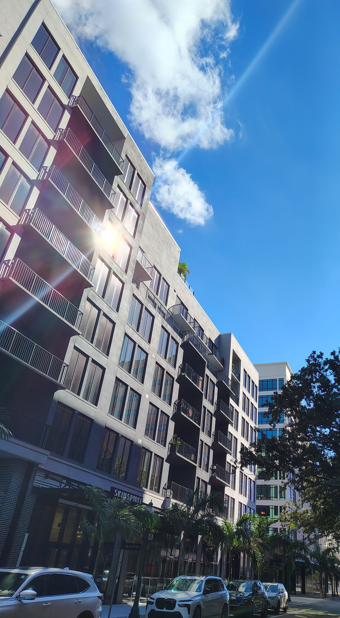 Modern apartment building against a bright blue sky with a few clouds.