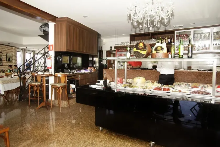 Elegante buffet de hotel com balcões pretos, lustre e decoração interior ornamentada.