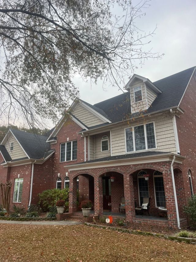 Brick house with arched porch and gabled roof, viewed from the front under overcast skies