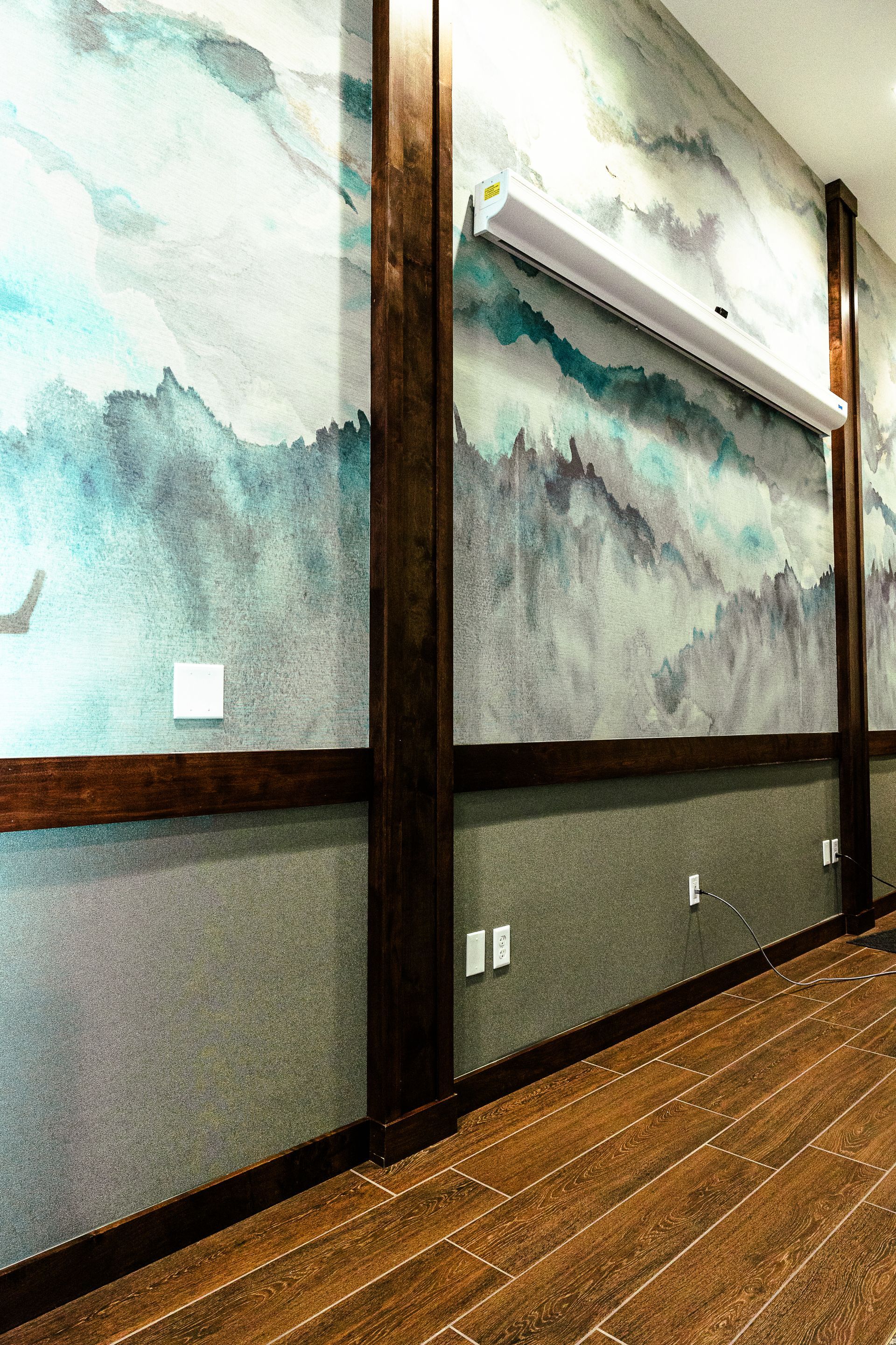 A hallway with a painting on the wall and a wooden floor.