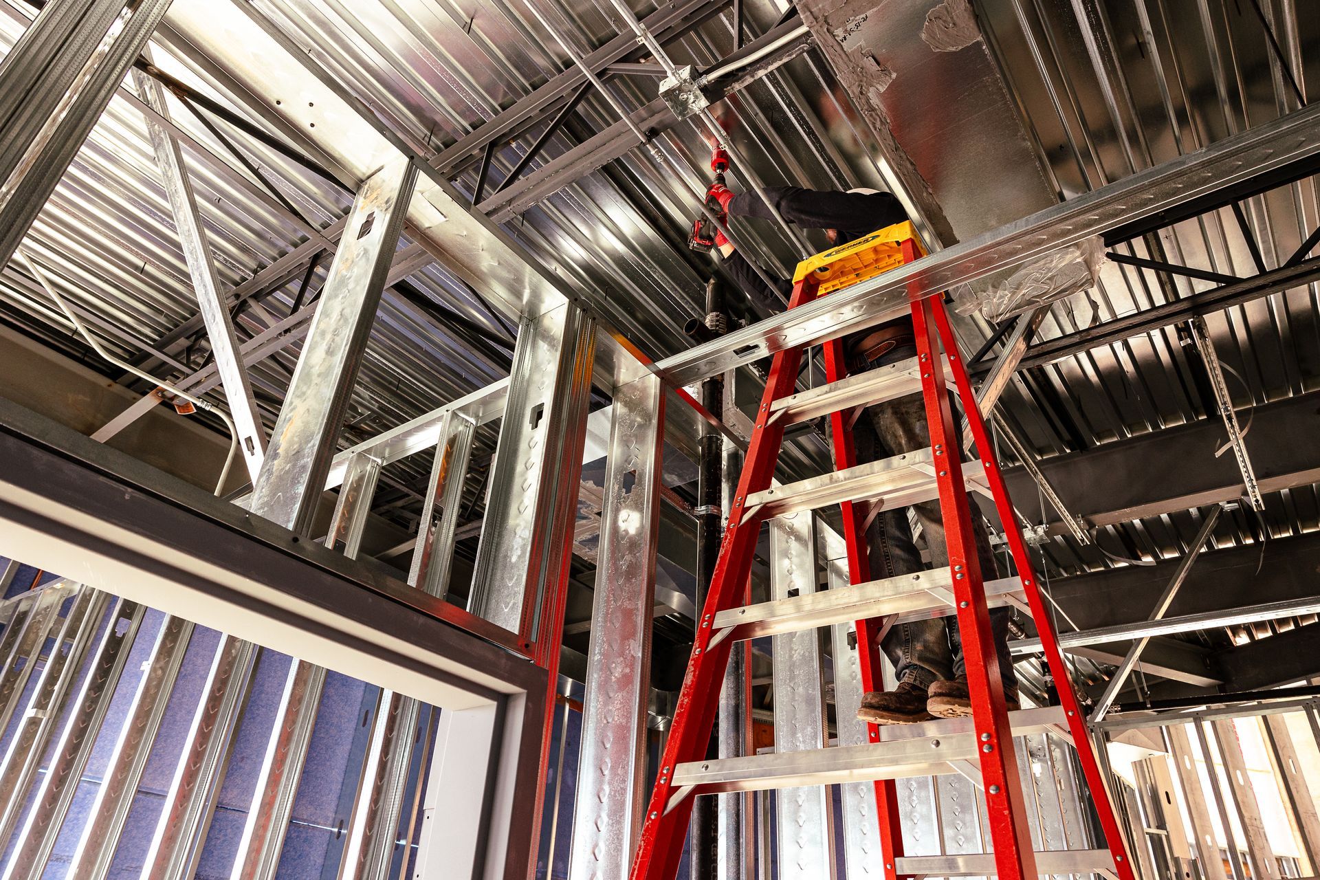 A man is standing on a ladder in a building under construction.