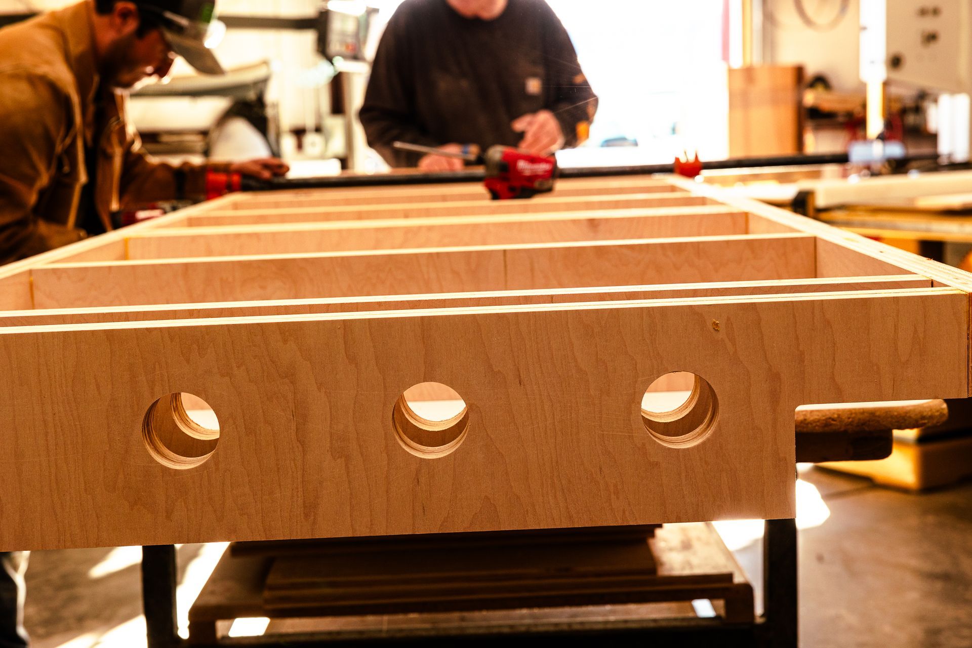 Two men are working on a large piece of wood