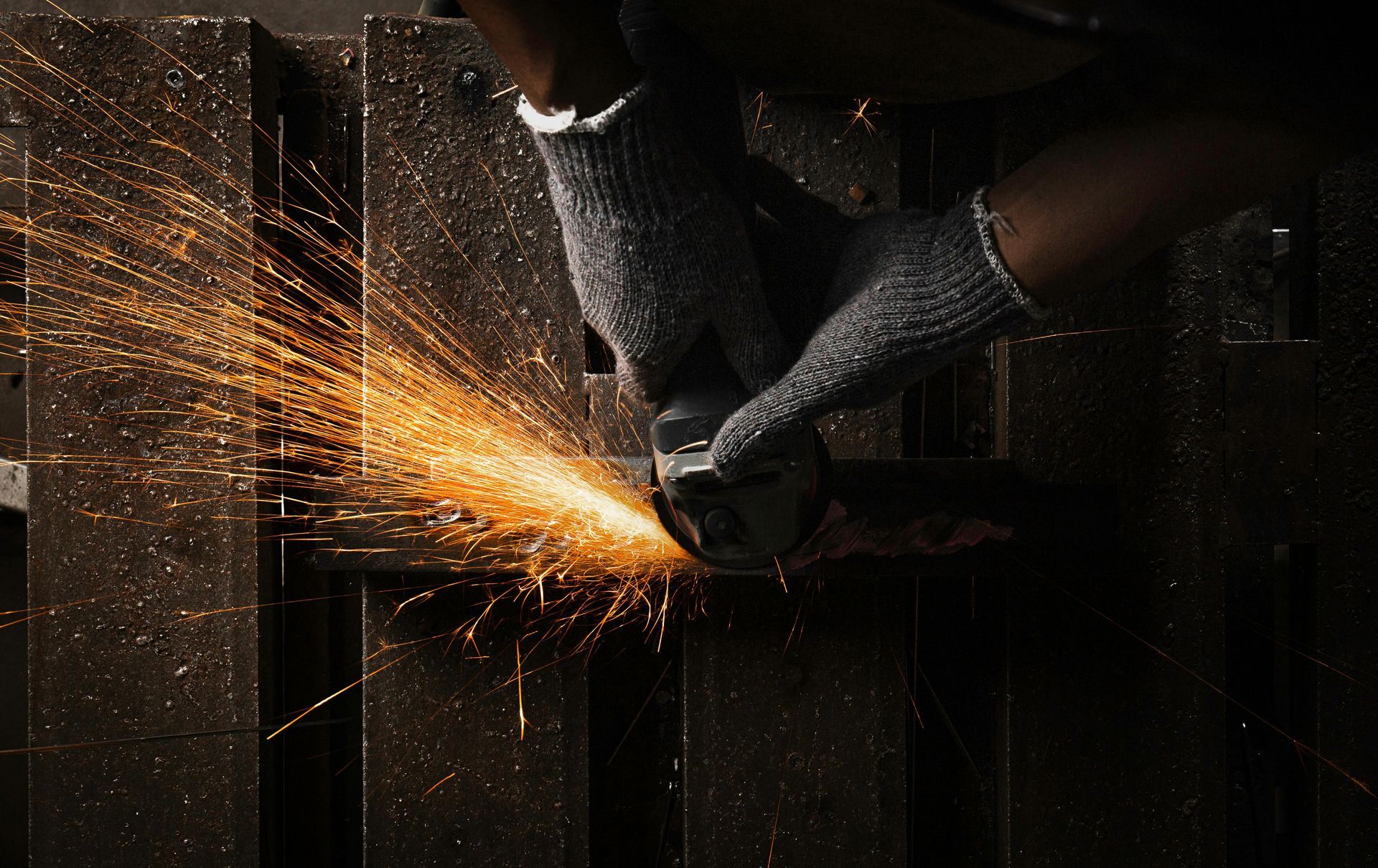 A person is using a grinder to cut a piece of metal.