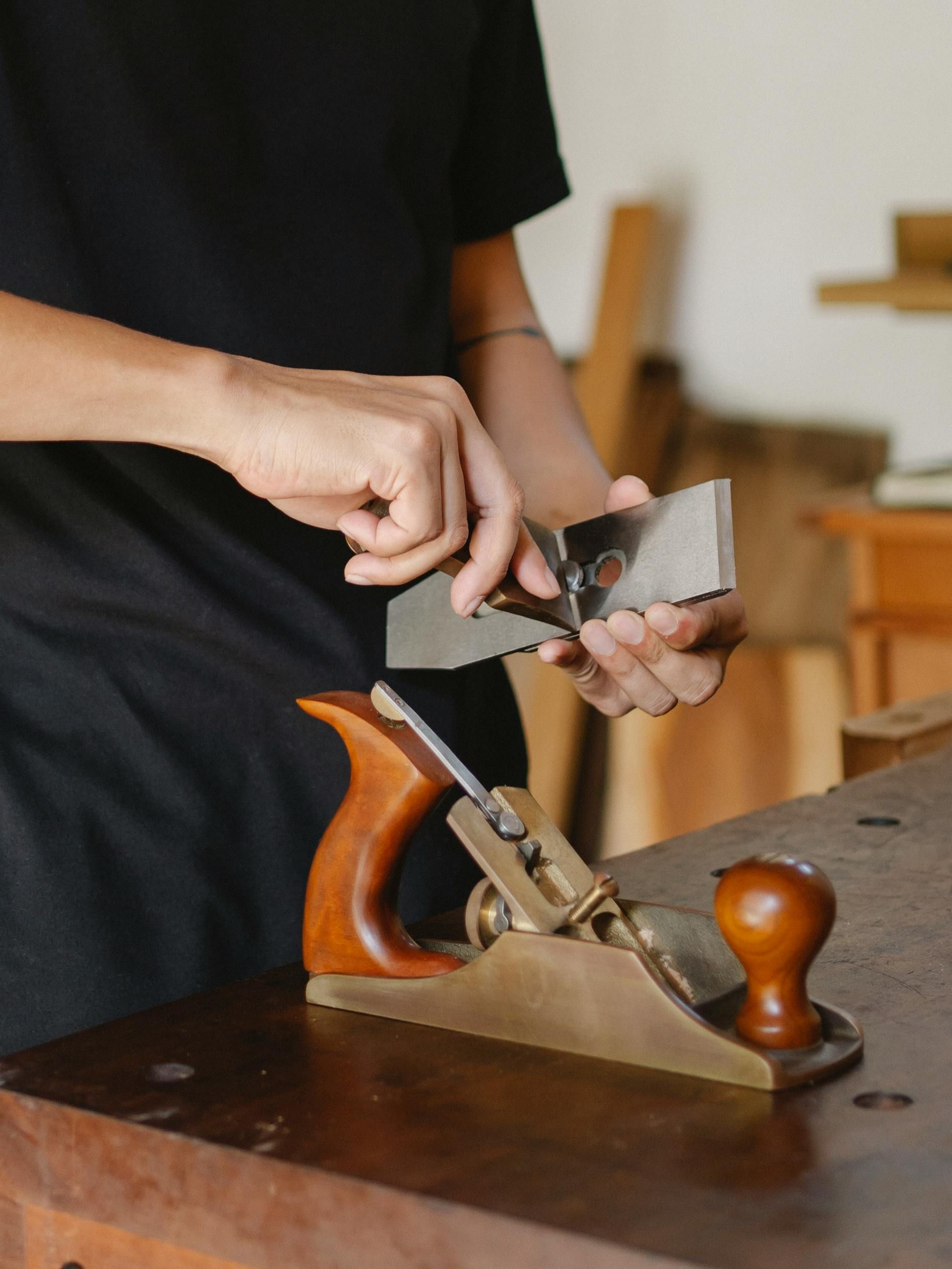 A person is using a plane on a wooden table.
