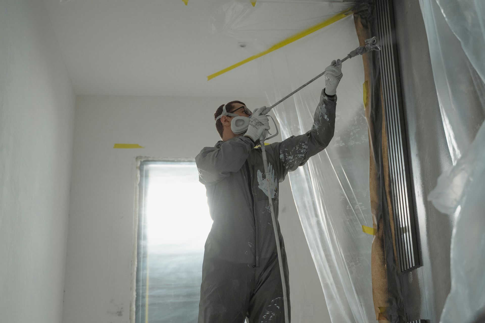 A person is using a paint roller to paint a wall