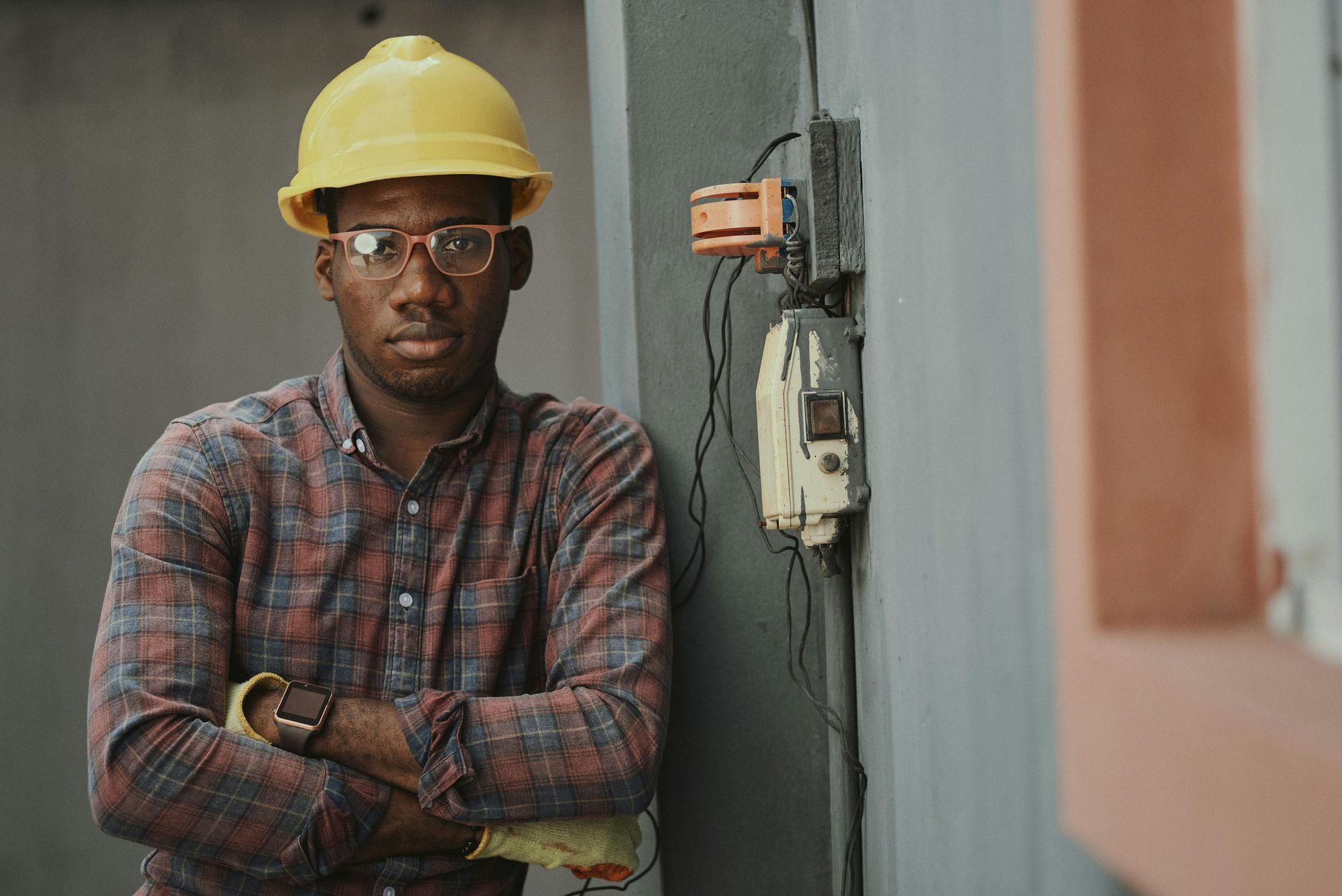 A man wearing a hard hat and glasses is standing with his arms crossed.