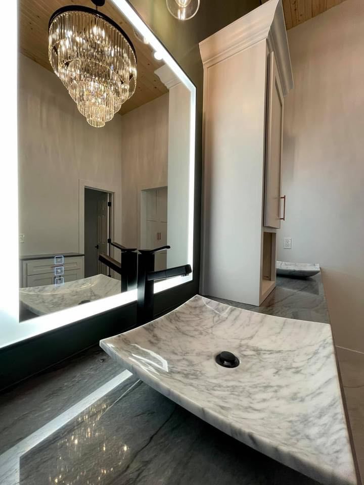a bathroom with a sink , mirror and chandelier .