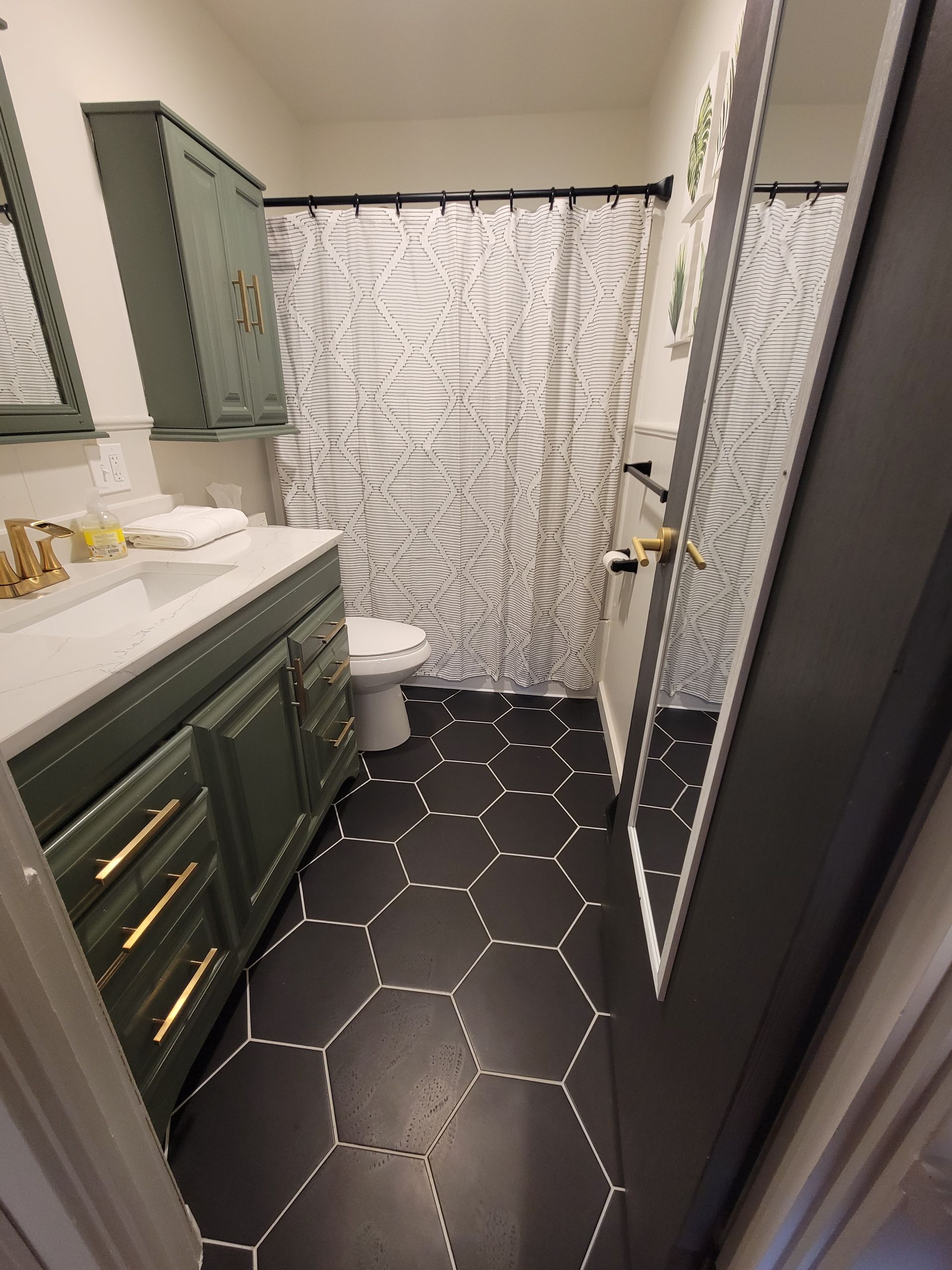 a bathroom with a toilet , sink , mirror and shower curtain .