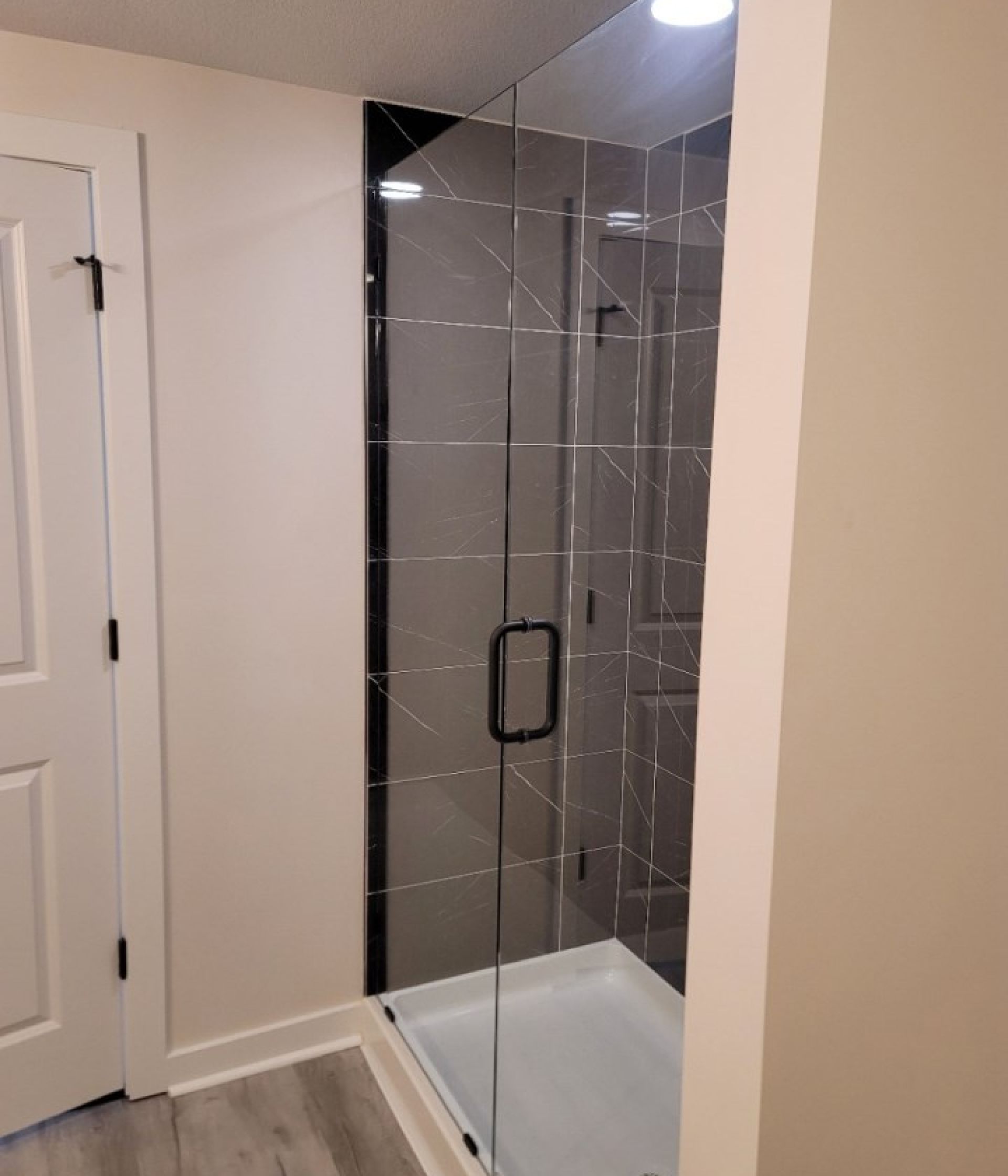 a bathroom with a walk in shower with a black handle