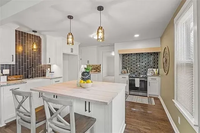 a kitchen with white cabinets and stainless steel appliances and a large island .