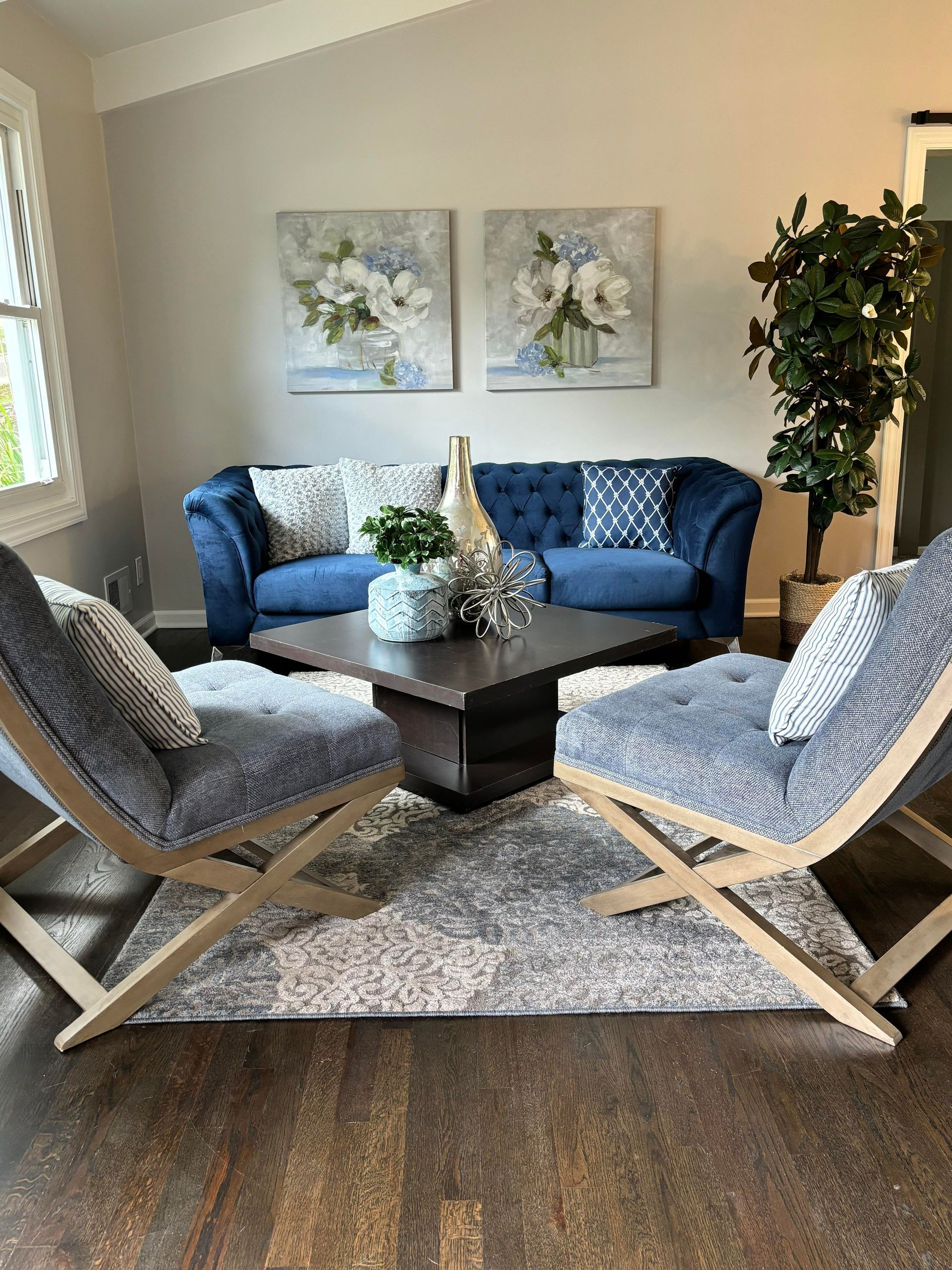 a living room with a blue couch , two chairs , and a coffee table .