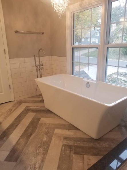 free-standing white porcelain soaker tub by a full length window