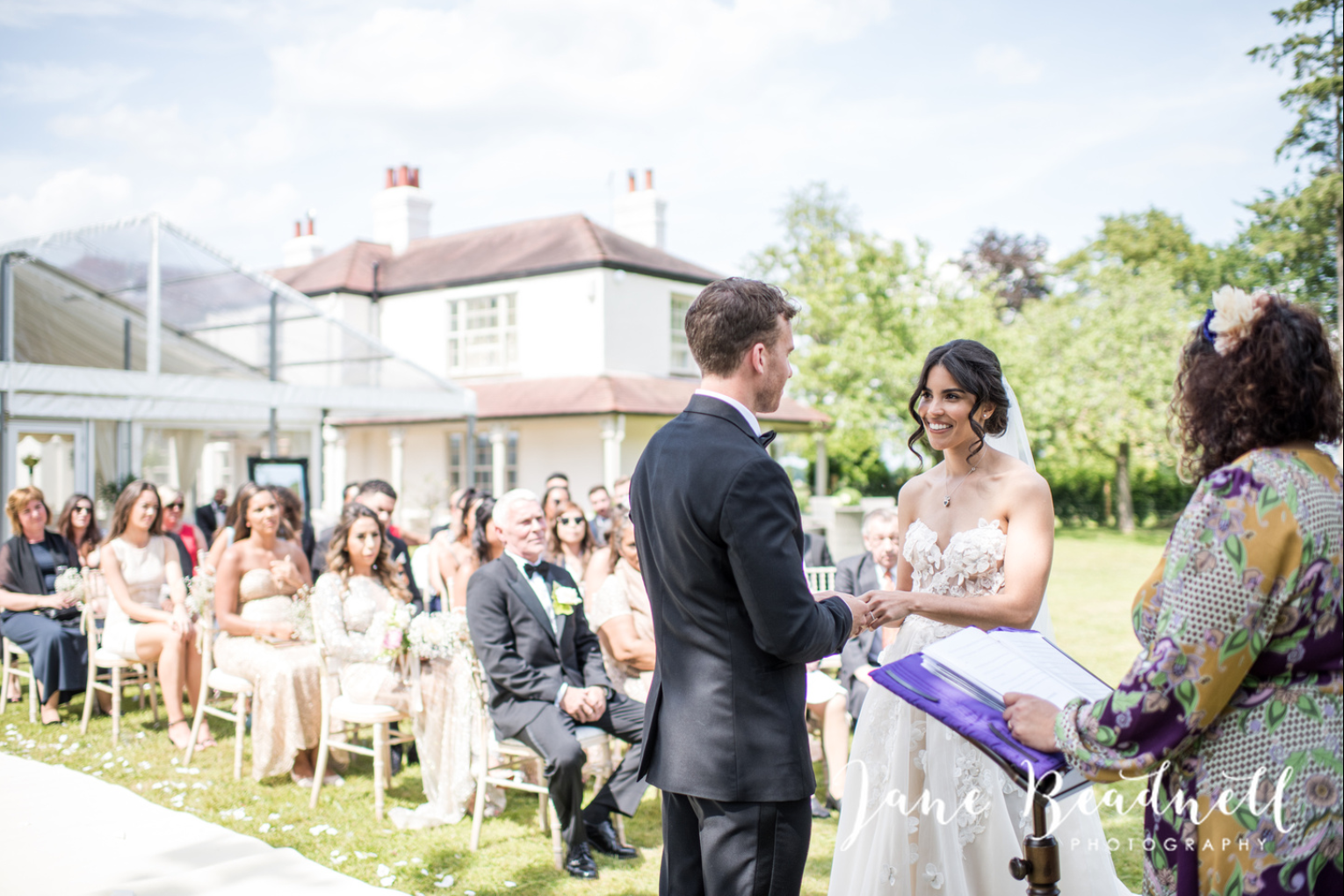 A bride and groom are holding hands during their wedding ceremony.