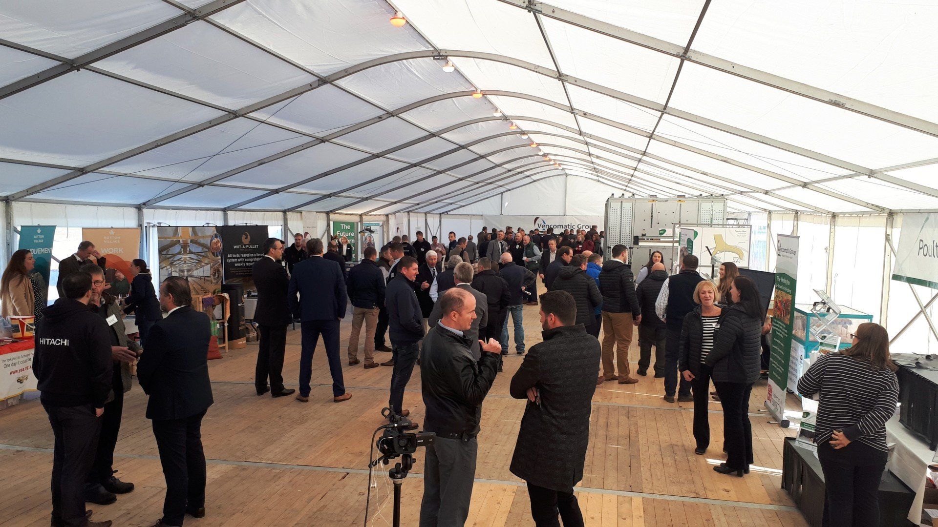 A large group of people are standing under a tent.
