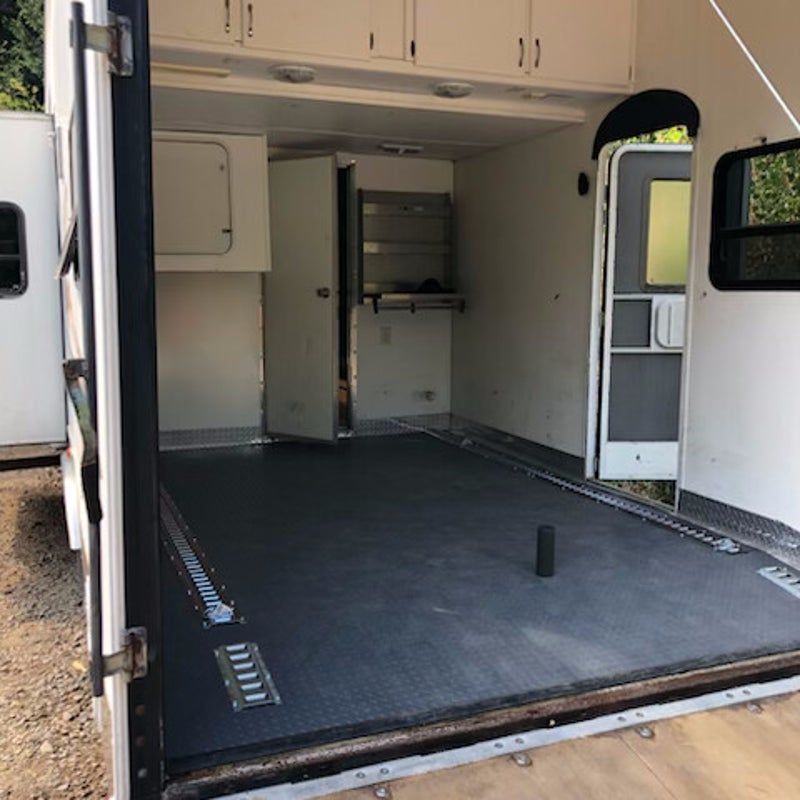 Empty cargo van interior with open rear doors, black floor, and built-in shelving.