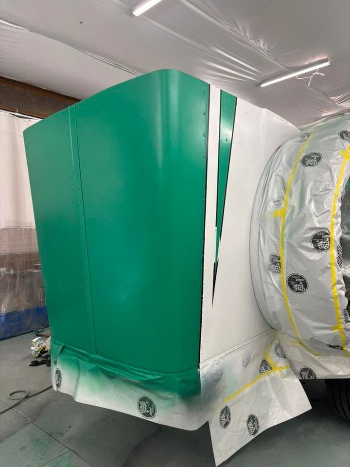 Large green industrial machine wrapped in protective plastic inside a workshop.