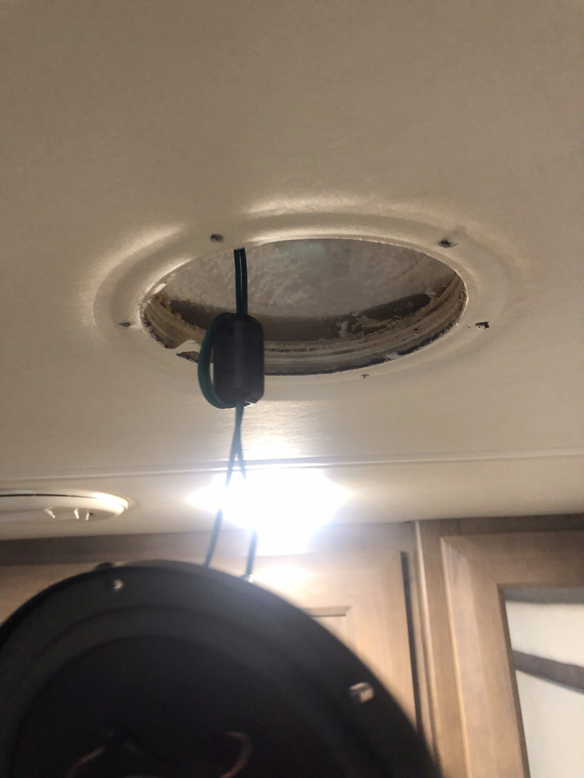 Ceiling vent with a hanging black cord or device above a bright doorway in a room