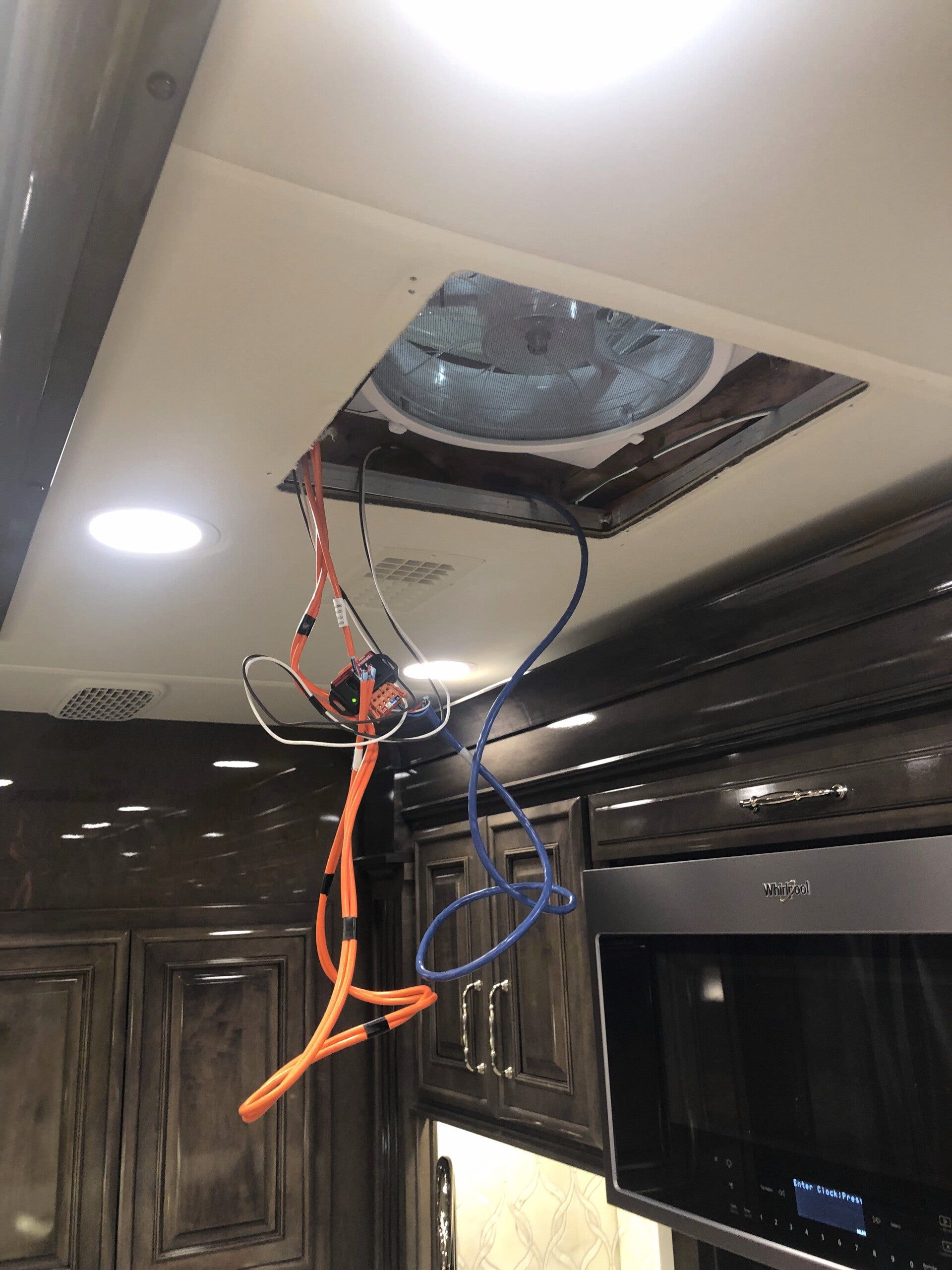 Ceiling AC unit with exposed wires hanging in a room, next to a TV and windows.
