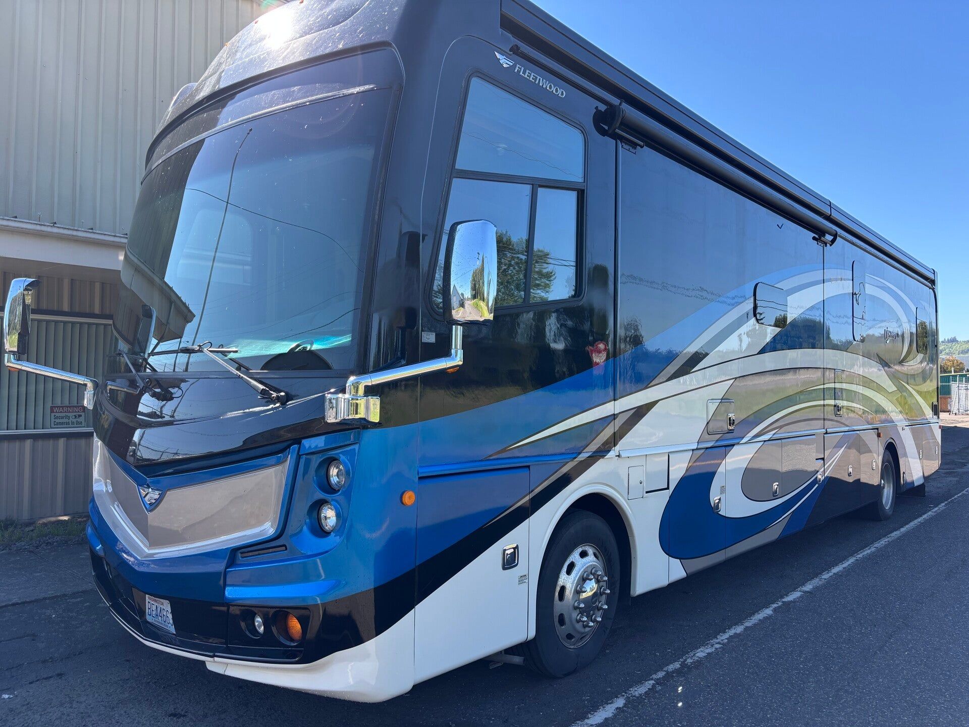 Blue and white coach bus parked outdoors beside a building