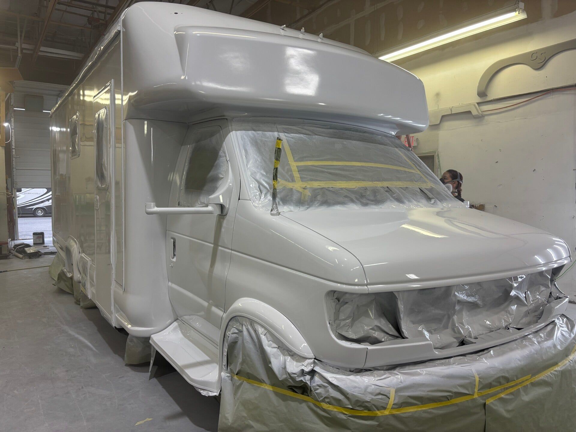 White semi-truck in a paint booth, masked and wrapped for painting or refinishing.