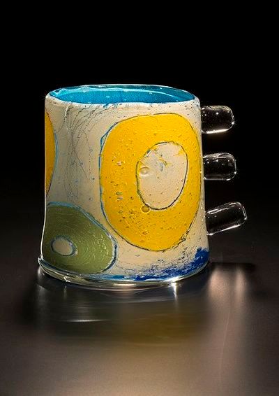 Glass mug with white textured body, blue and yellow circular designs.