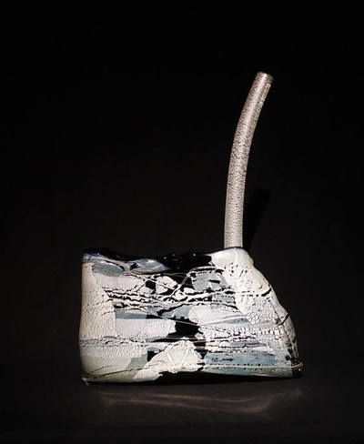 Abstract sculpture. White and blue textured base with a curved, silver tube rising from it. Black background.