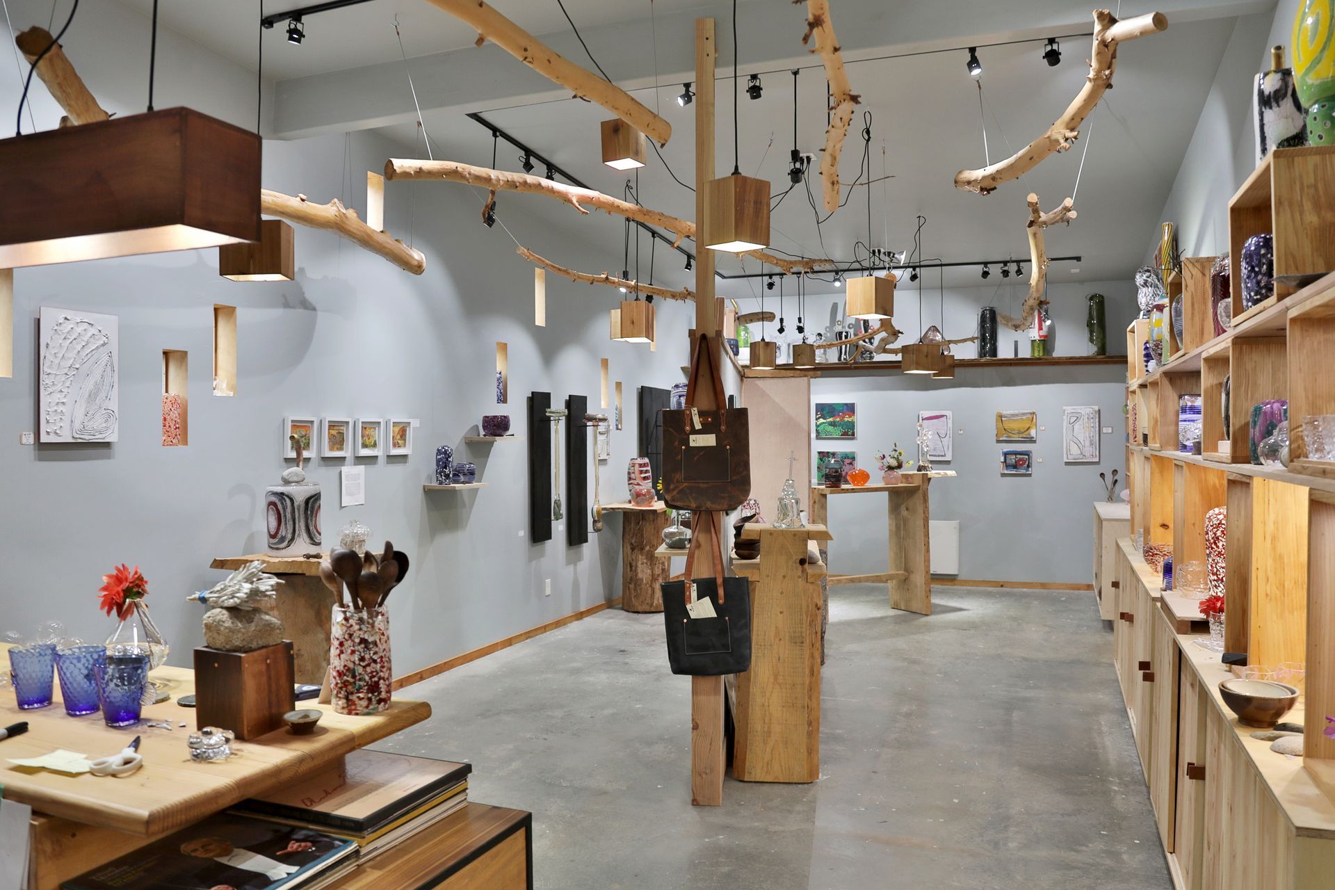 Art gallery interior with wooden fixtures, artwork, and various sculptures.