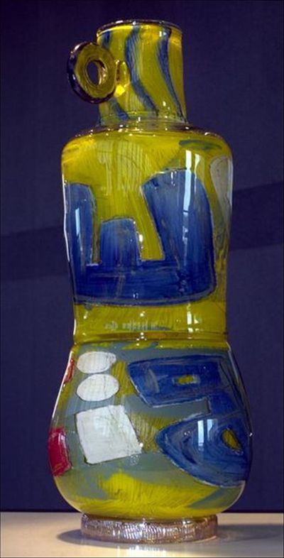 Colorful glass sculpture with blue and yellow patterns, on a pedestal.