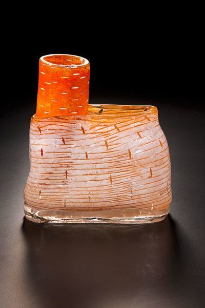 Glass sculpture of a textured orange and white structure with a cylindrical form on top.