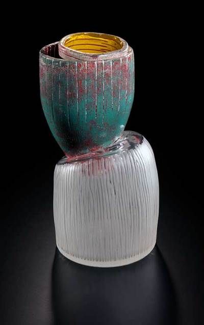 Sculptural glass vase, cylindrical bottom in silver, tilted green top with red accents, and yellow interior.