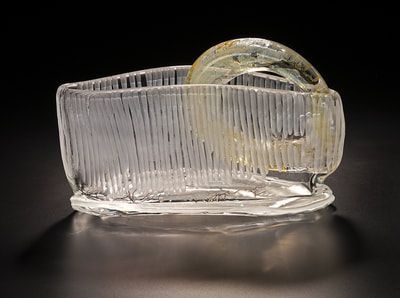 Clear glass sculpture with a ribbed rectangular base and a curved handle.