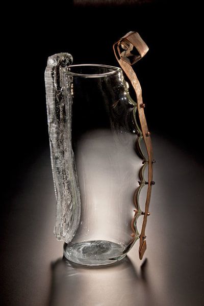 Glass and metal sculpture with a clear glass body and copper handle.