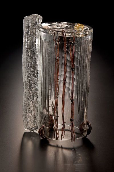 Glass sculpture with embedded brown sticks, and an icy, attached piece.