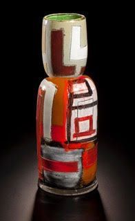 Abstract glass vase with red, white, brown, and green geometric patterns.