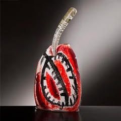 Red, white, and black abstract glass sculpture with a clear stem, set against a dark gradient background.