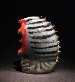 Sculptural ceramic form. Grey and black striped with red accent. Gold spikes.