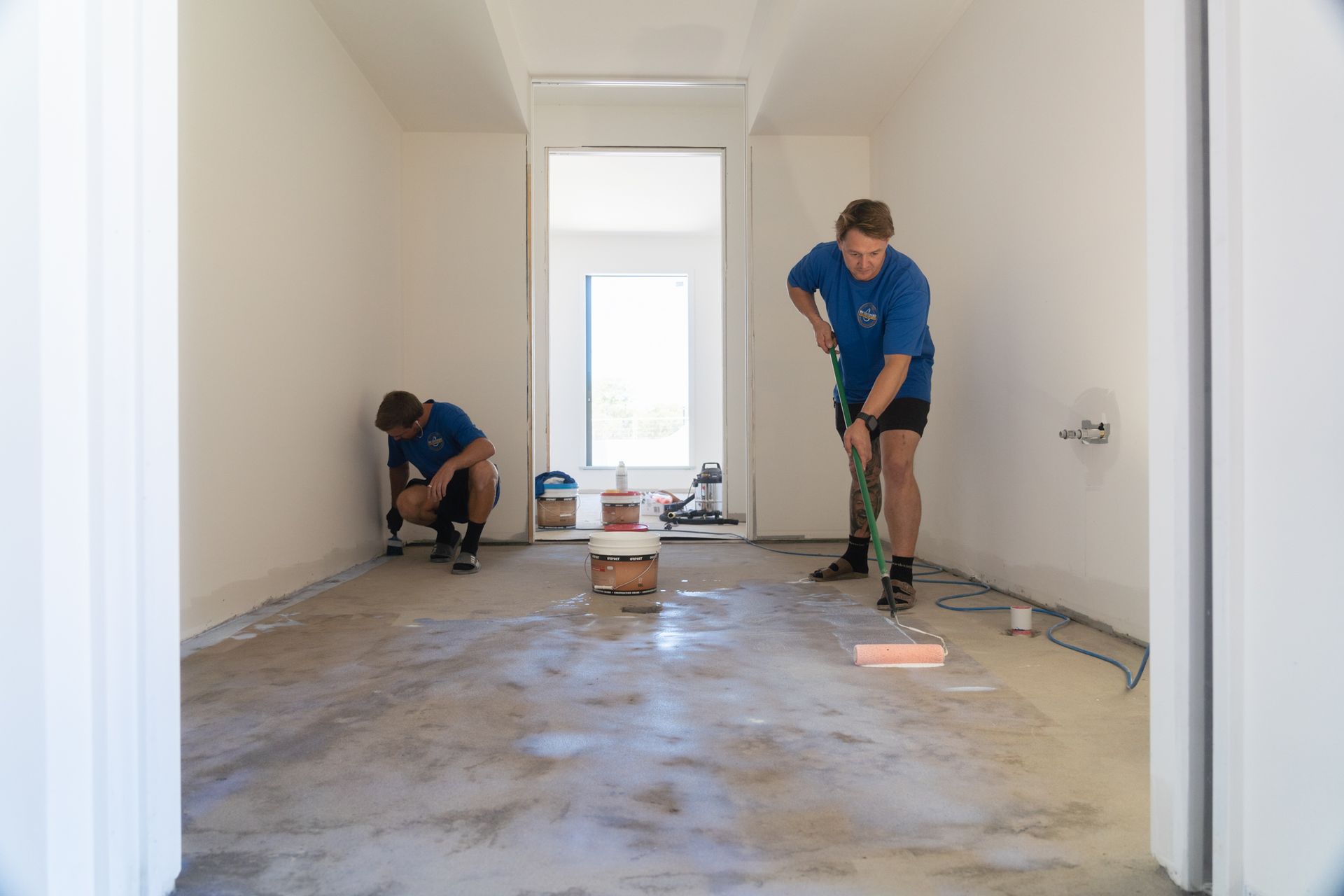Two men are working on a floor in a room.