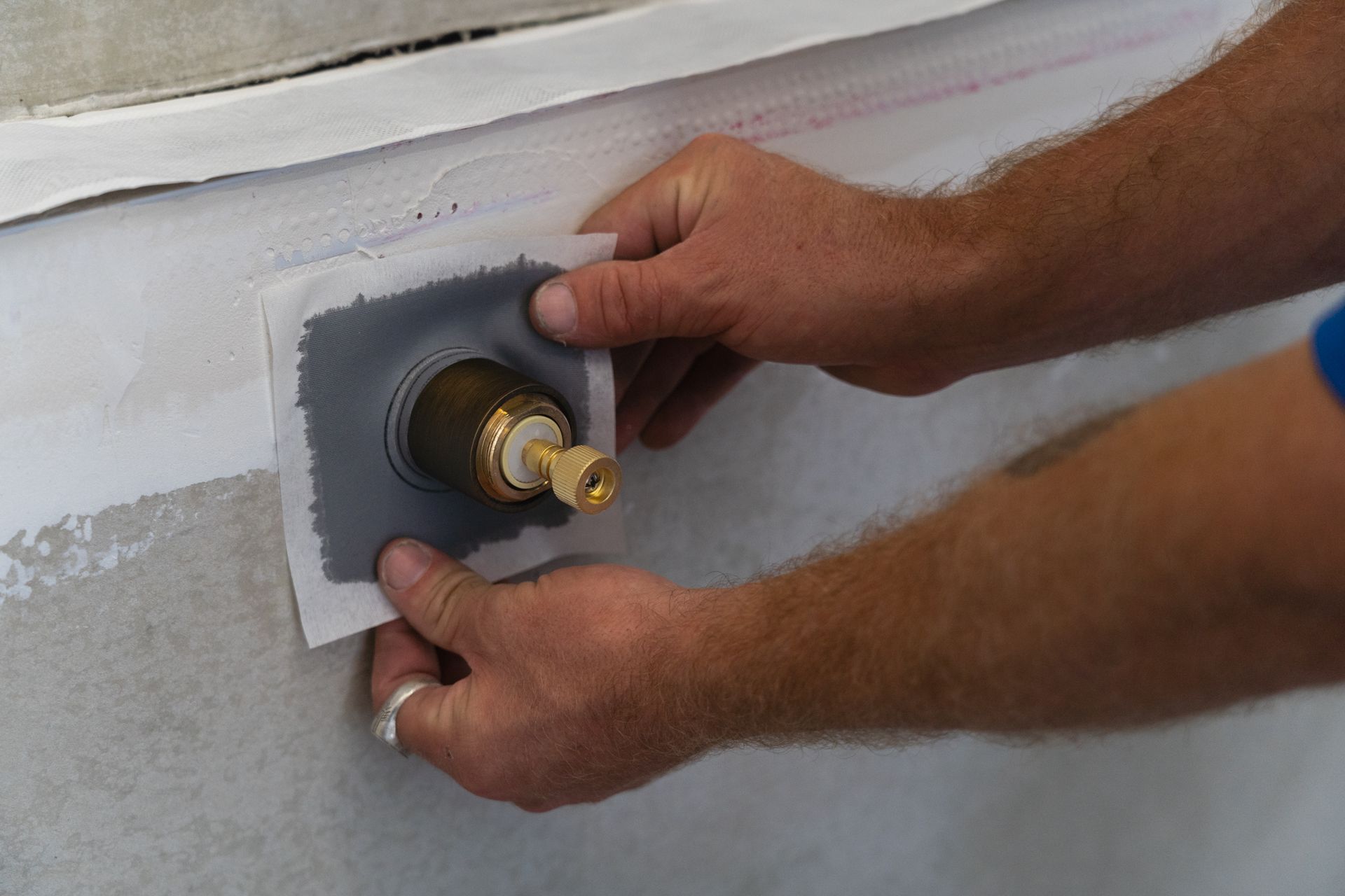 A person is installing a faucet on a wall.