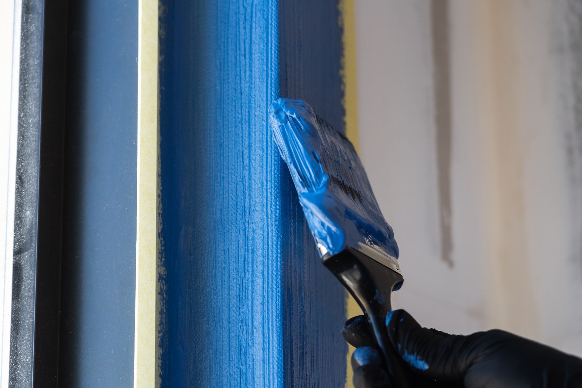 A person is painting a blue wall with a brush.