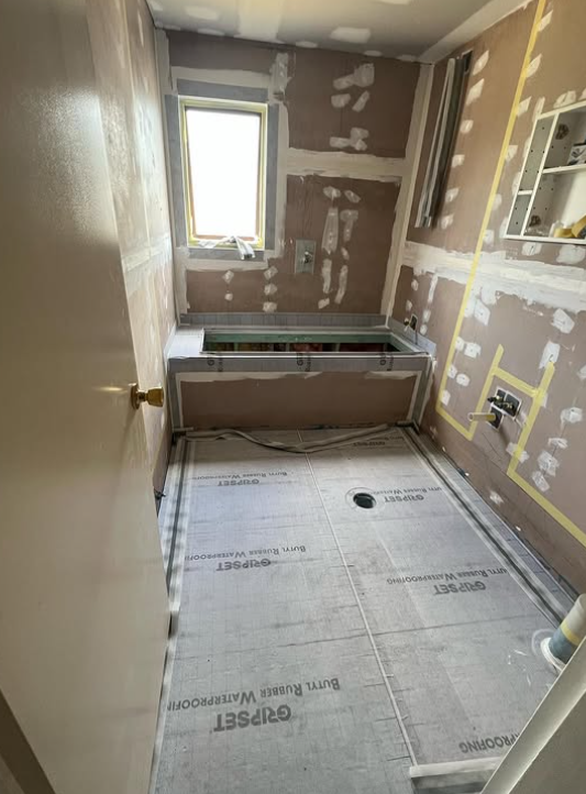 A bathroom under construction with a bathtub and a window.