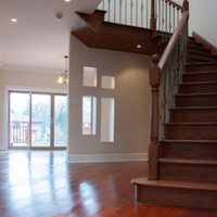 Bright empty foyer with hardwood floors, staircase, and sliding glass doors leading outside.