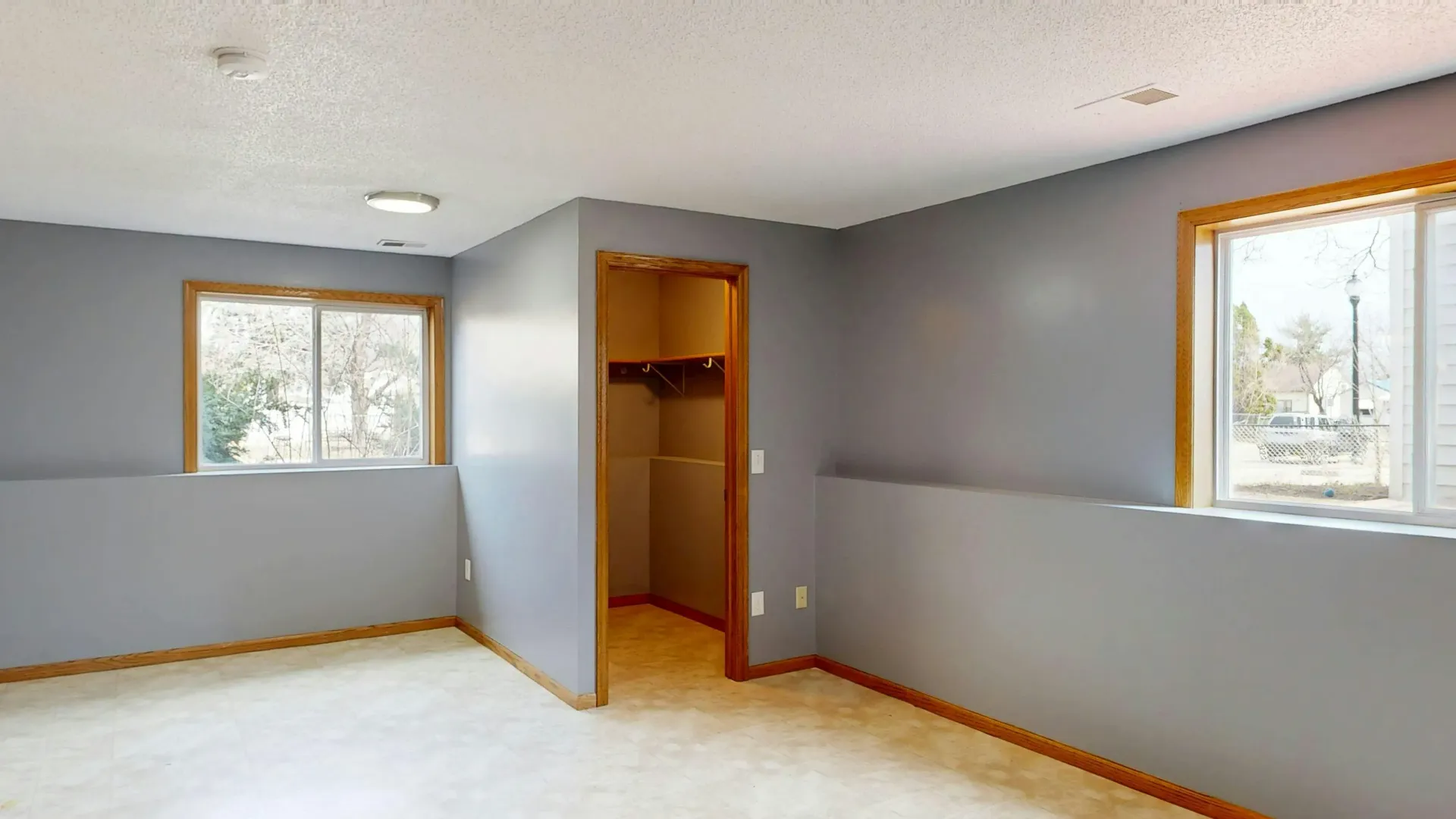 Empty Gray Bedroom With Two Windows Open