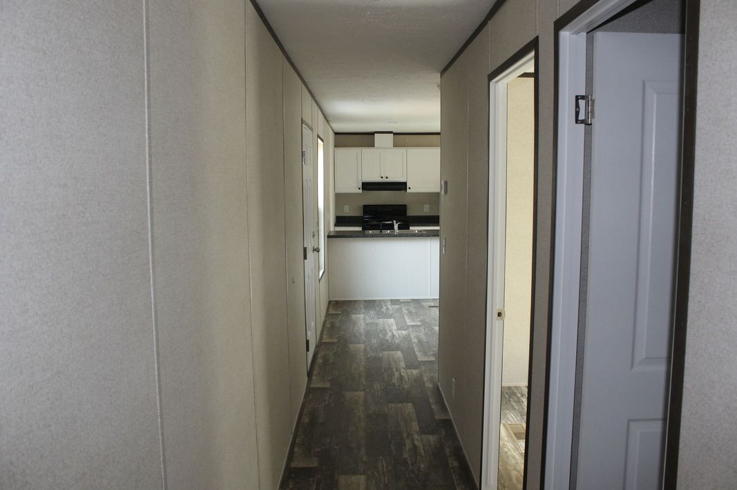 A long hallway leading to a kitchen and a bathroom in a mobile home.