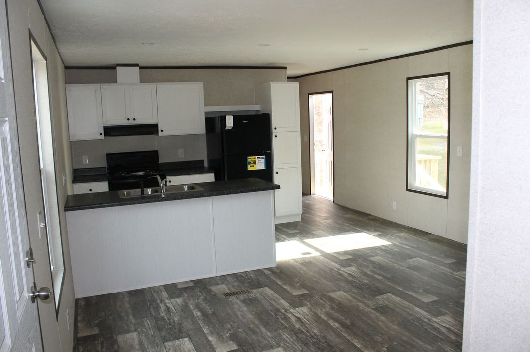 An empty kitchen with a black refrigerator and white cabinets
