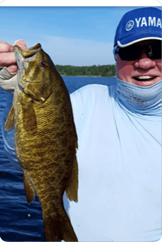 Person on a boat holding up a large fish against a blue lake and sky