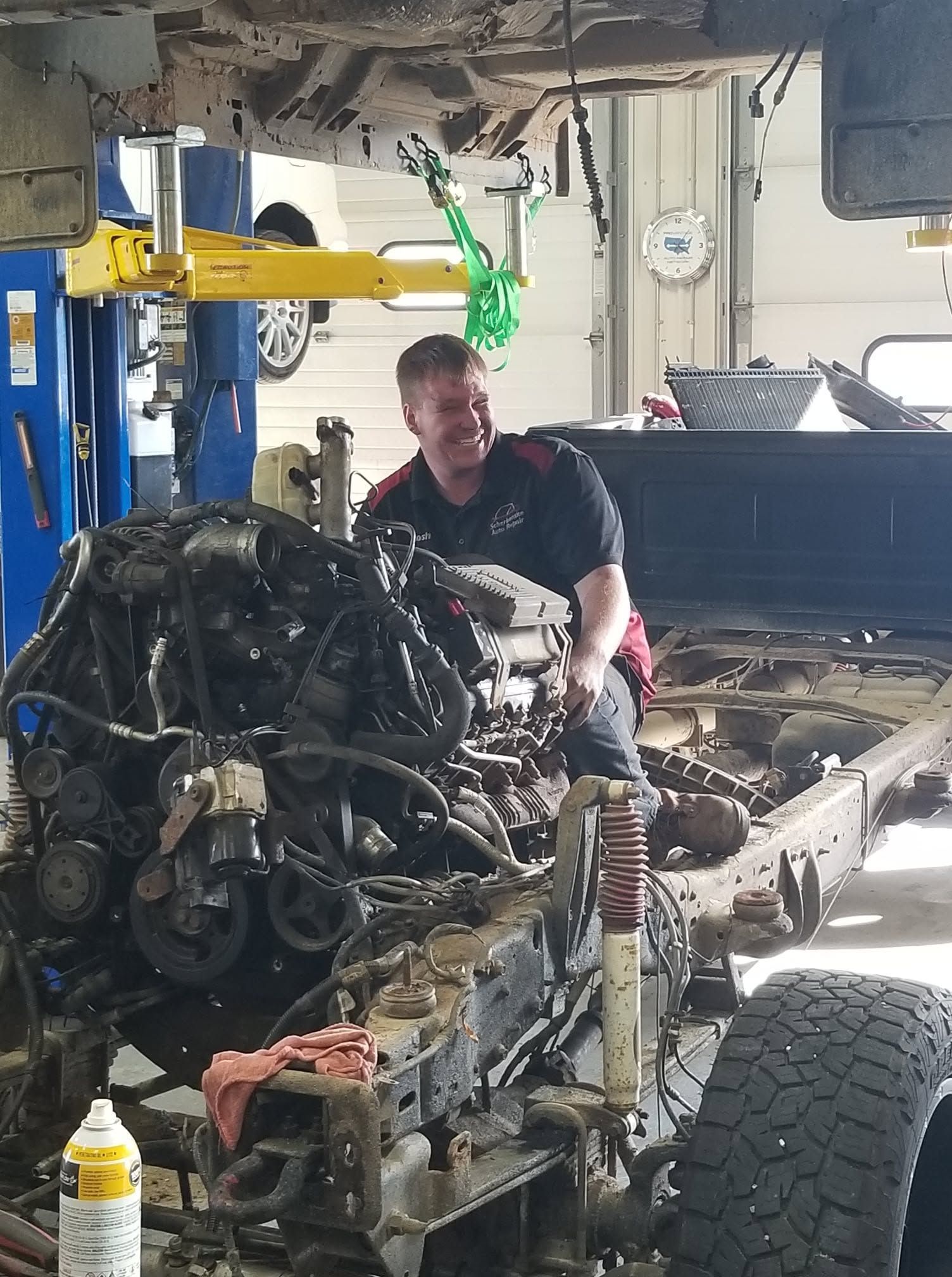 Mechanic working on a partially disassembled truck in a garage, with engine and chassis exposed. | Scherbenske Auto Repair Inc