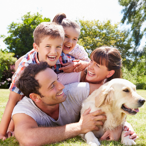 A family is laying in the grass with a dog.